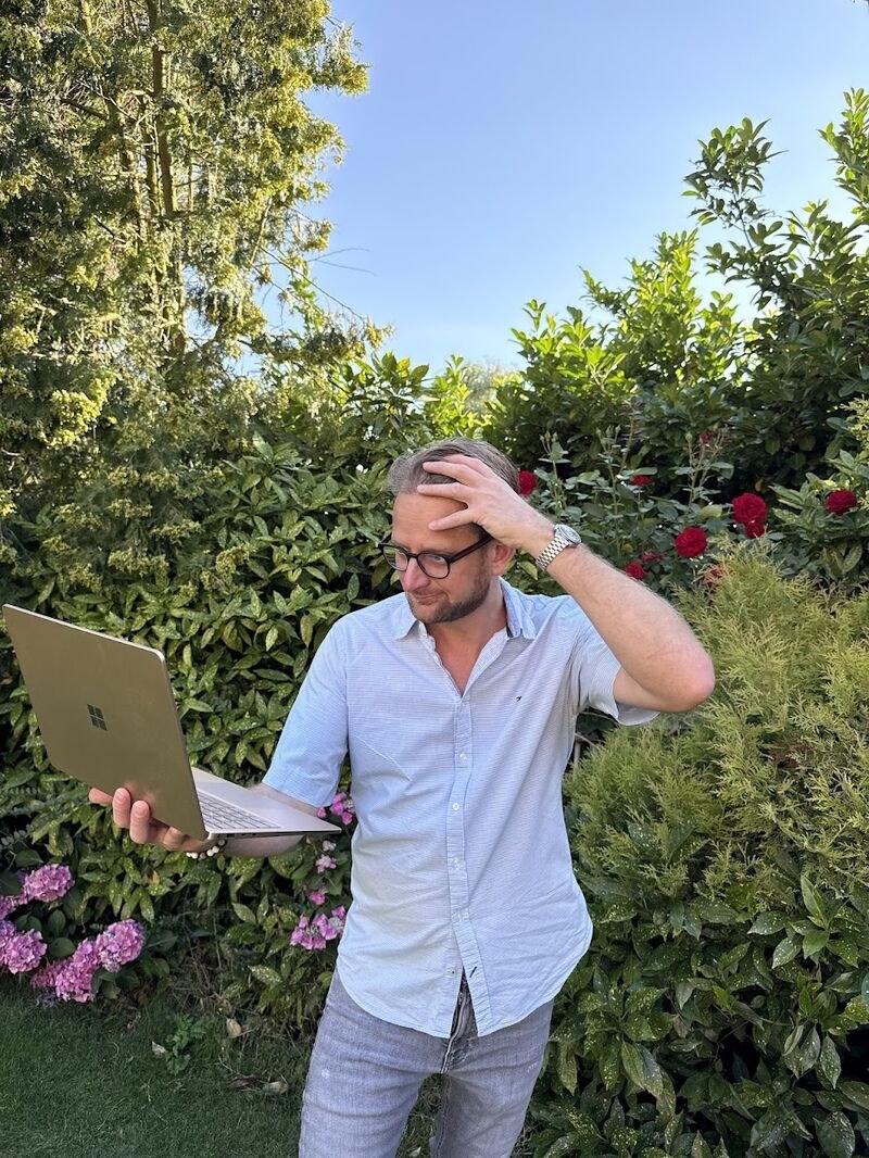 Boris in de tuin met een laptop in de hand en een hand aan zijn hoofd